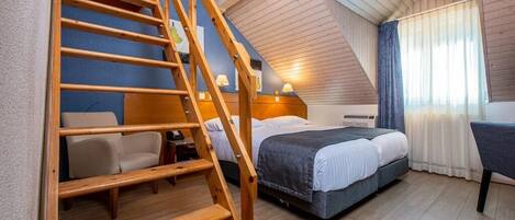 A bedroom with a wooden staircase, a bed, a desk, and a chair.