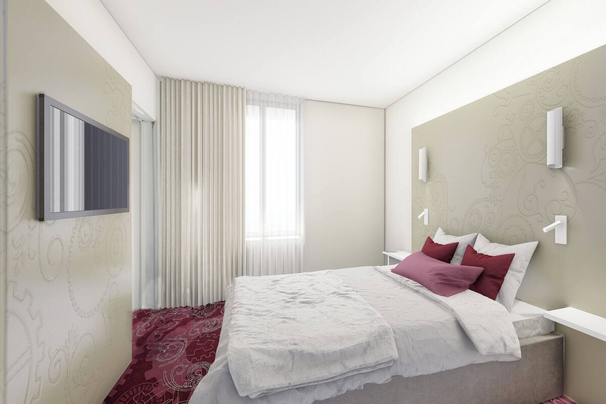Ein modernes Hotelzimmer mit einem großen Bett, einem Flachbildfernseher und einem dekorativen Kopfteil.