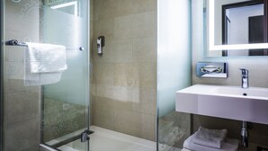 Un bany modern amb una dutxa envidriada, un lavabo blanc i un mirall gran.