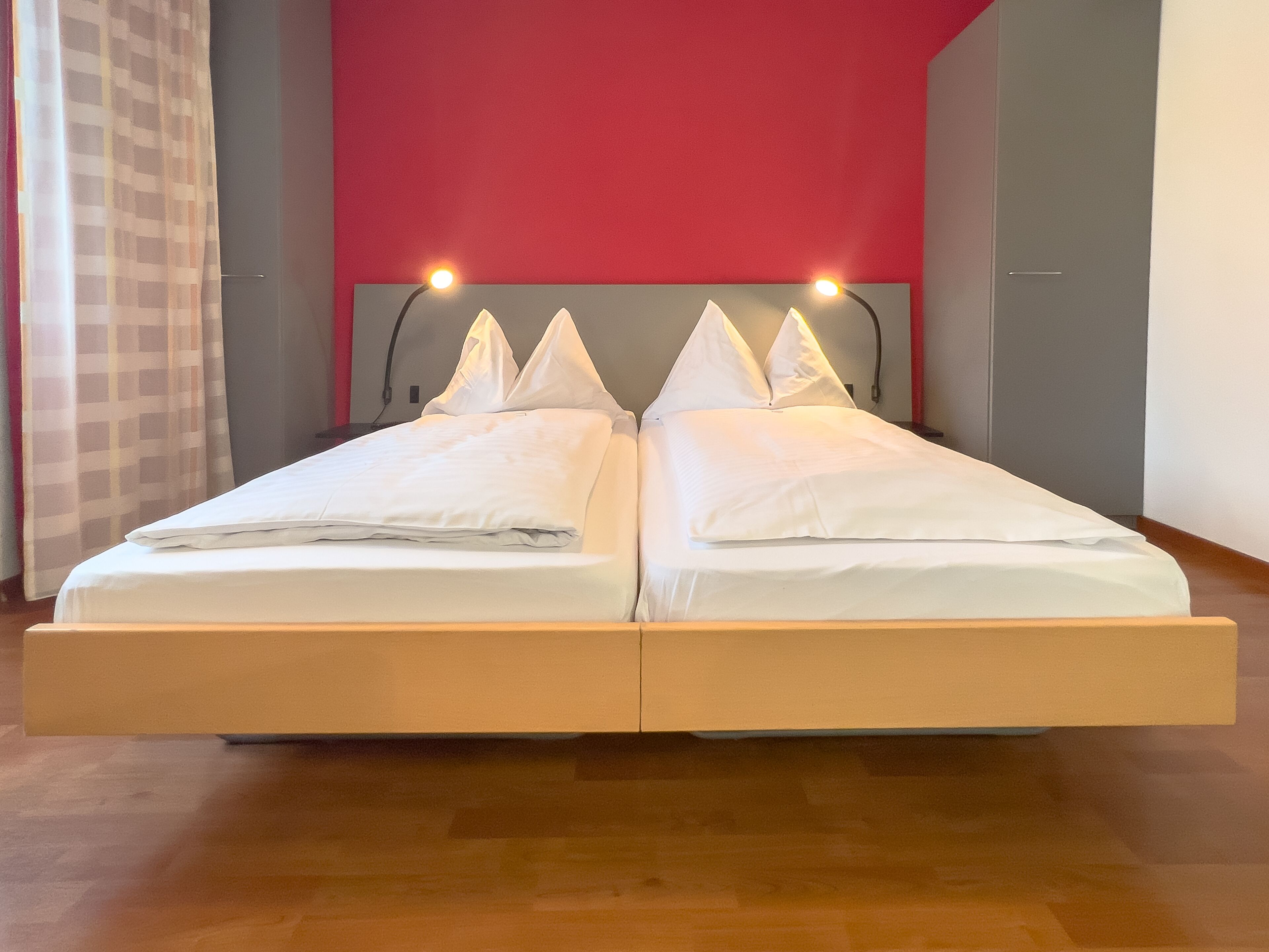 A double bed with a wooden frame, two bedside tables, and a headboard with integrated lighting.