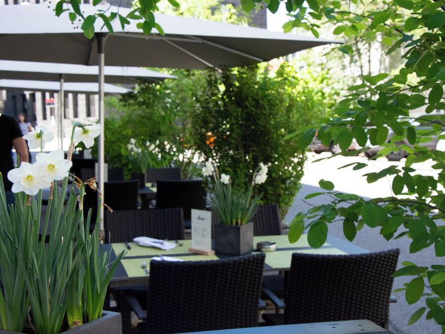 An outdoor seating area with tables and chairs, a covered umbrella, and a potted plant.