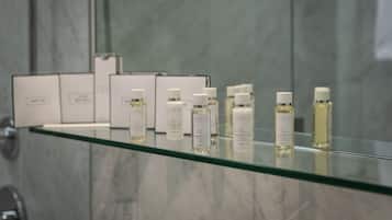 Une salle de bain avec une étagère en verre où sont exposés divers produits de toilette.