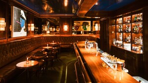 A bar area with wooden paneling, leather booths, and a well-stocked liquor shelf.