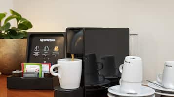 Ein Nespresso-Kaffeemaschinen-Setup mit einer Kaffeemaschine, Tassen und einem Kaffee-Pod-Halter auf einer Holztischplatte.