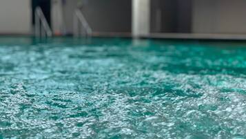 Primer plano de una piscina con agua cristalina y burbujas visibles, lo que indica movimiento del agua.