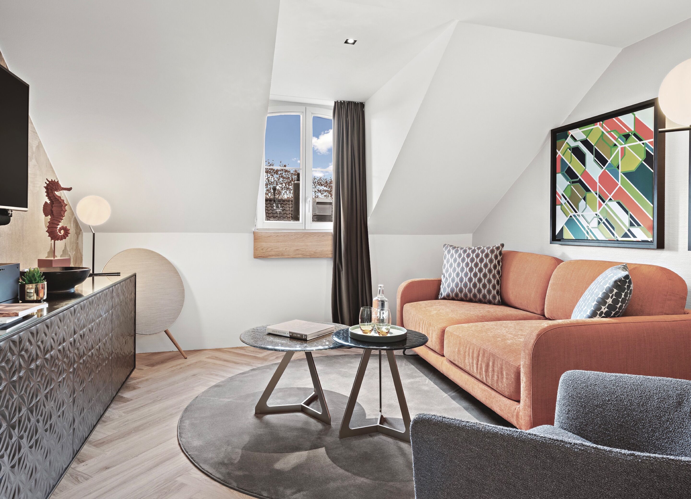 Un salon moderne avec un canapé, une table basse ronde, un fauteuil, une figurine décorative représentant un hippocampe et un tableau accroché au mur.