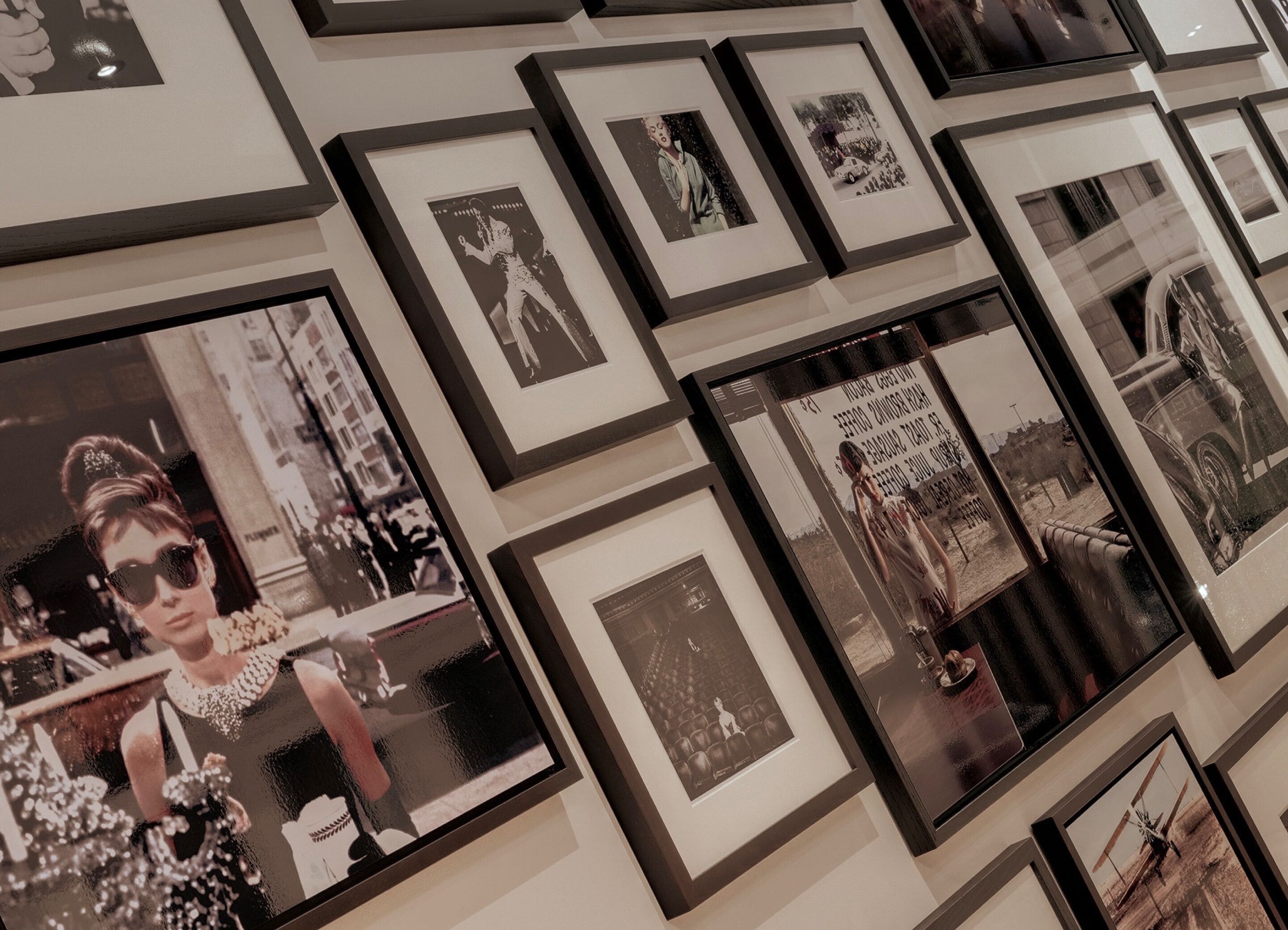 A wall with multiple framed photographs of various subjects, including people and cars, arranged in a grid pattern.
