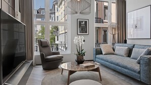 Una sala moderna con un sofá gris, un sillón gris y una mesa de centro con libros y una orquídea en maceta.