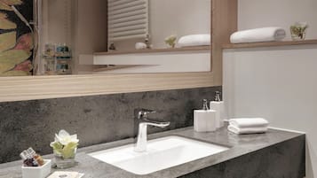 Ein modernes Badezimmer mit einer Granittafel, einem weißen Waschbecken und einem großen Spiegel.