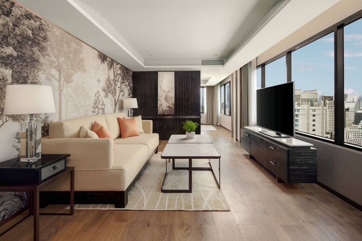 A modern living room with a sofa, coffee table, TV, and city view.