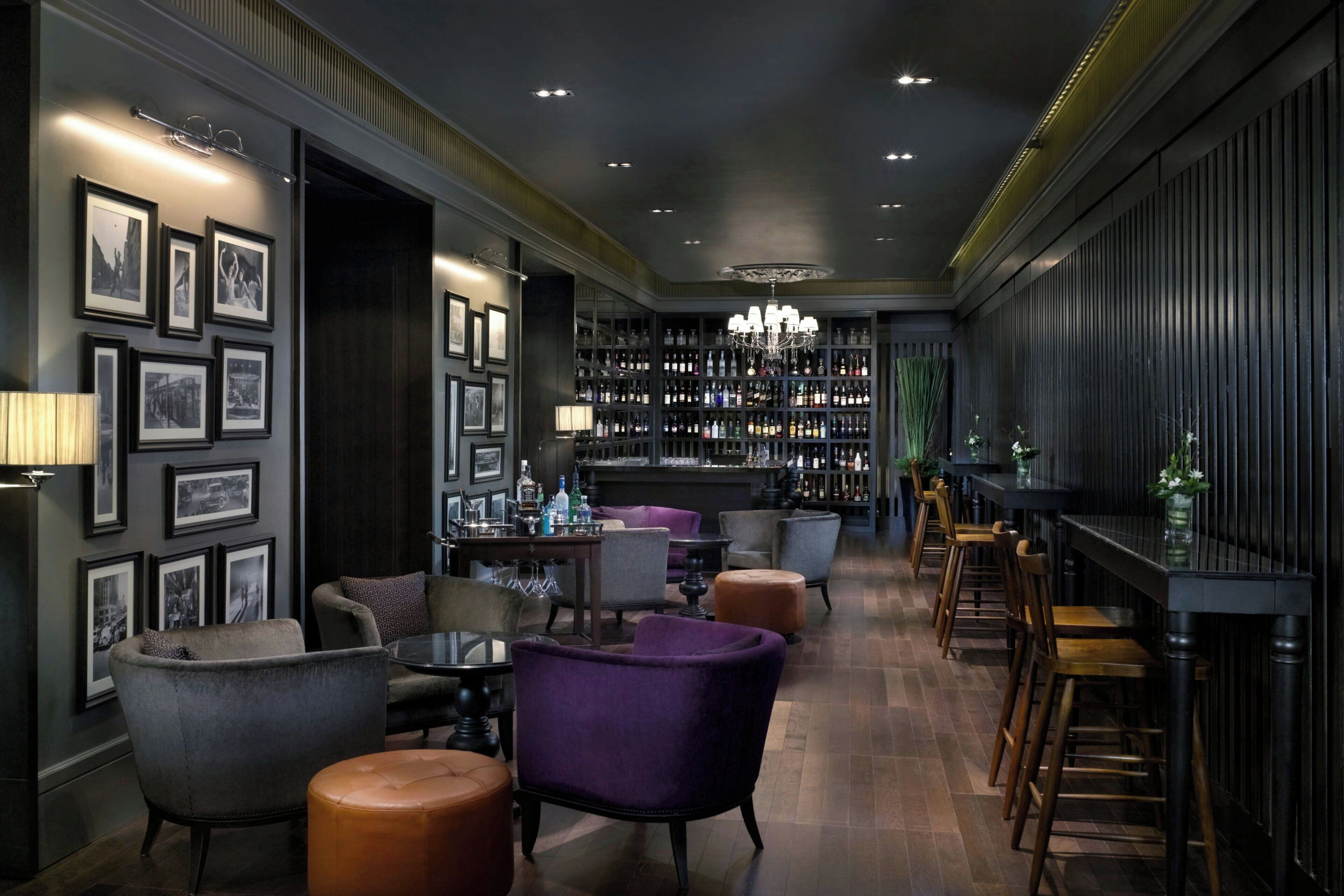 A bar area with seating, a bar counter, and a chandelier.