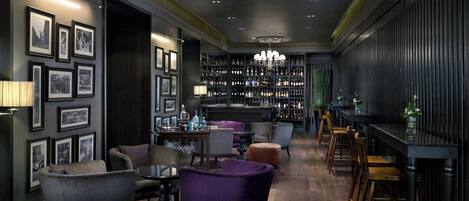A bar area with seating, a bar counter, and a chandelier.