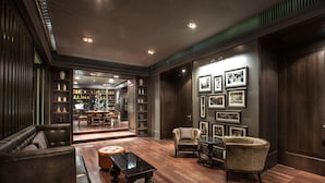 Una habitación amplia con un sofá de cuero, una mesa redonda y una estantería llena de libros y objetos decorativos.