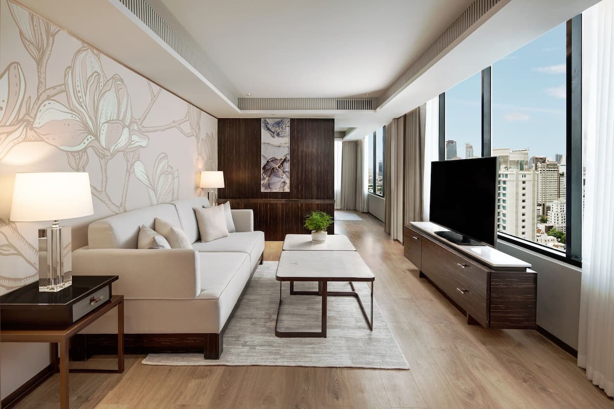 A modern living room with a sofa, coffee table, TV, and a city view through large windows.