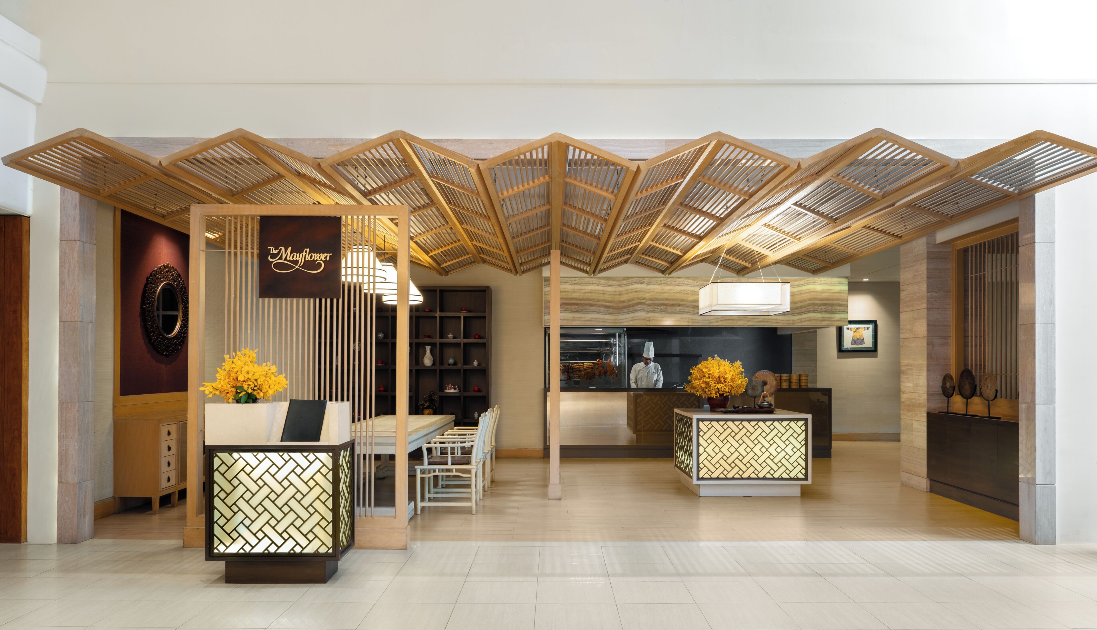 A reception area with a modern design, featuring a reception desk, seating area, and a view into the kitchen.