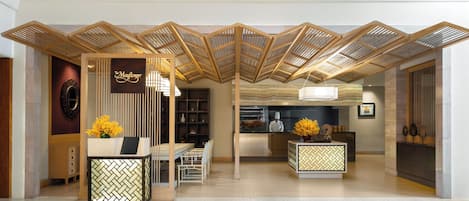 A reception area with a modern design, featuring a reception desk, seating area, and a view into the kitchen.