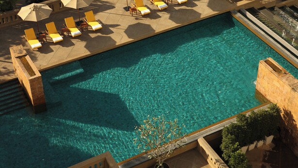 A large rectangular pool with clear blue water, surrounded by sun loungers and umbrellas. - Dusit Princess Srinakarin (Bangkok)