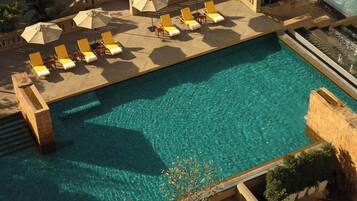 Relax by the pool surrounded by sun loungers and shaded by umbrellas.
