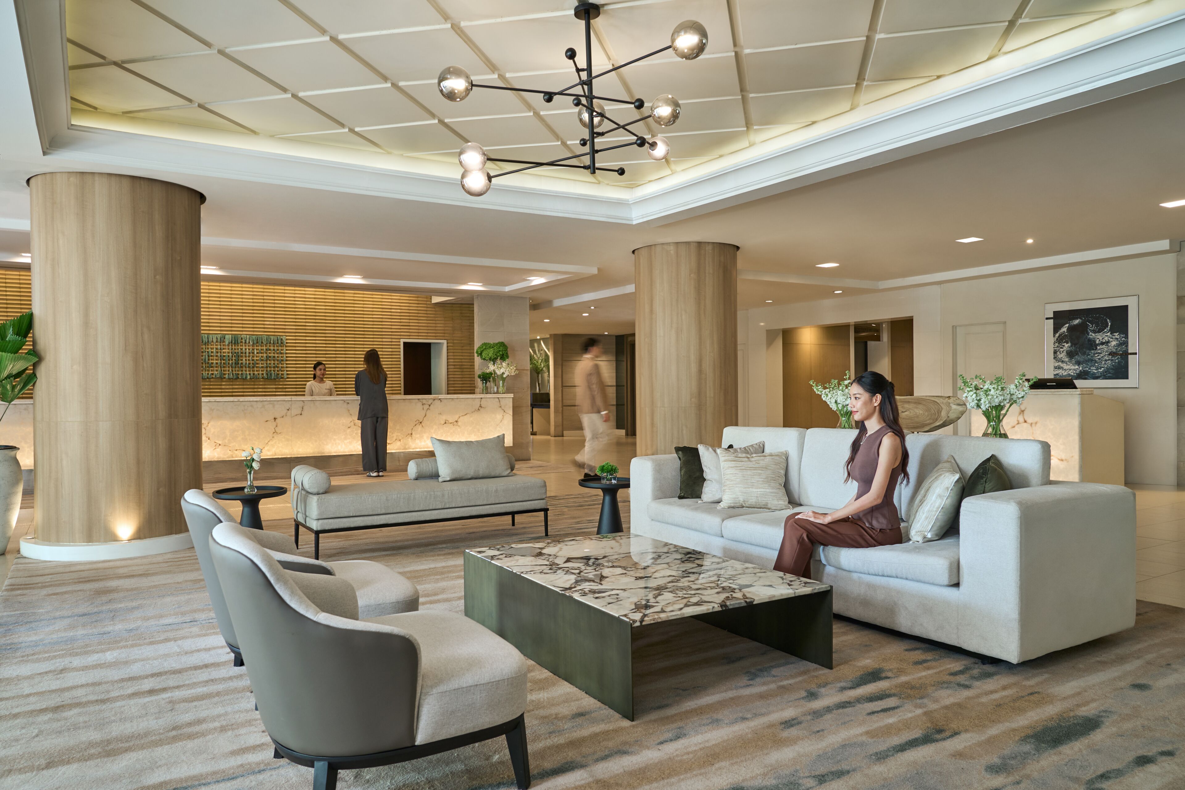 A spacious lobby with a reception desk, seating area, and a modern chandelier.