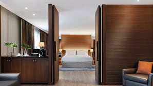 A modern hotel room with a large bed, a desk with a computer, and a seating area with a chair and a sofa. - Dusit Princess Srinakarin (Bangkok)