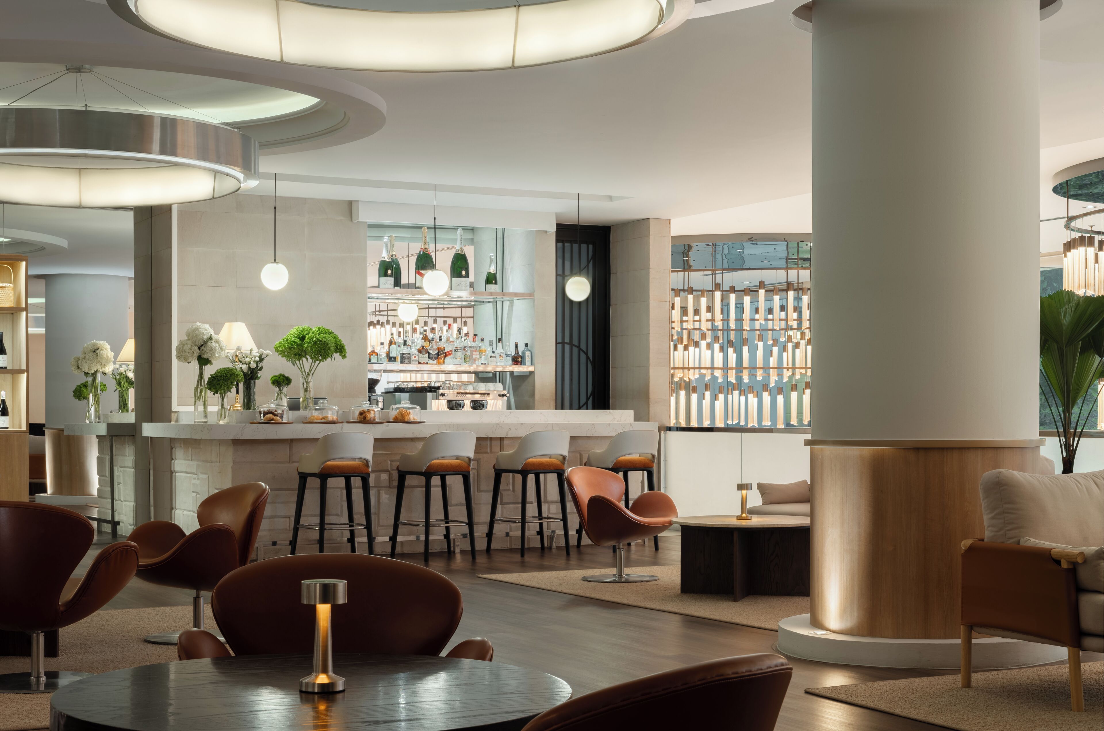 Eine moderne Bar mit hohen Hockstühlen, einer Theke und einer Auswahl an Flaschen.