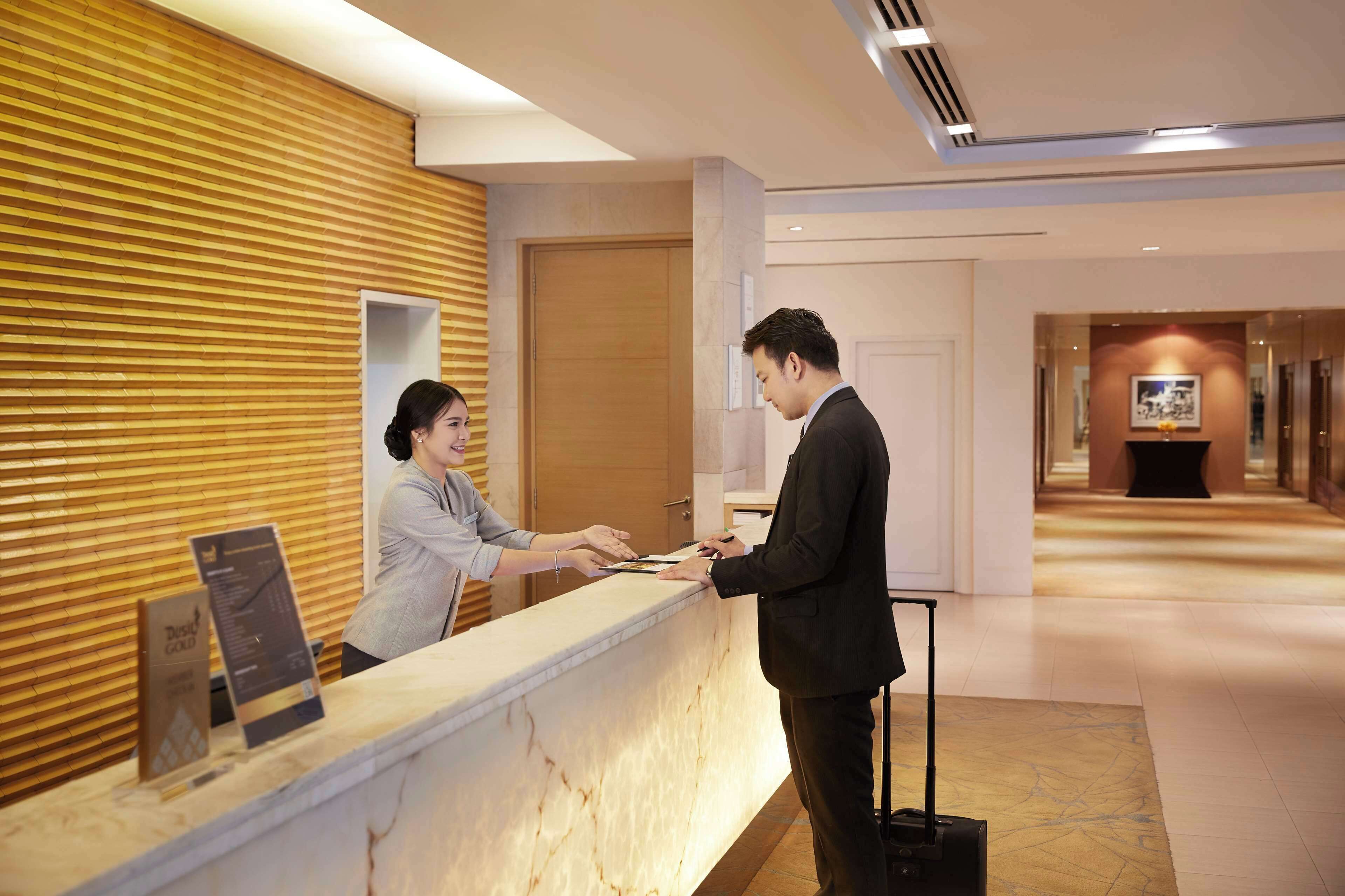 A hotel reception desk with a wooden panel wall, a marble counter, and a framed picture on the wall.