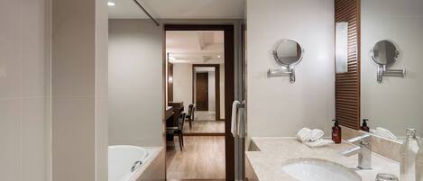A modern bathroom with a bathtub, two sinks, and a mirror.