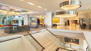 A modern hotel lobby with a glass staircase, seating areas, and contemporary lighting fixtures. - Dusit Princess Srinakarin (Bangkok)