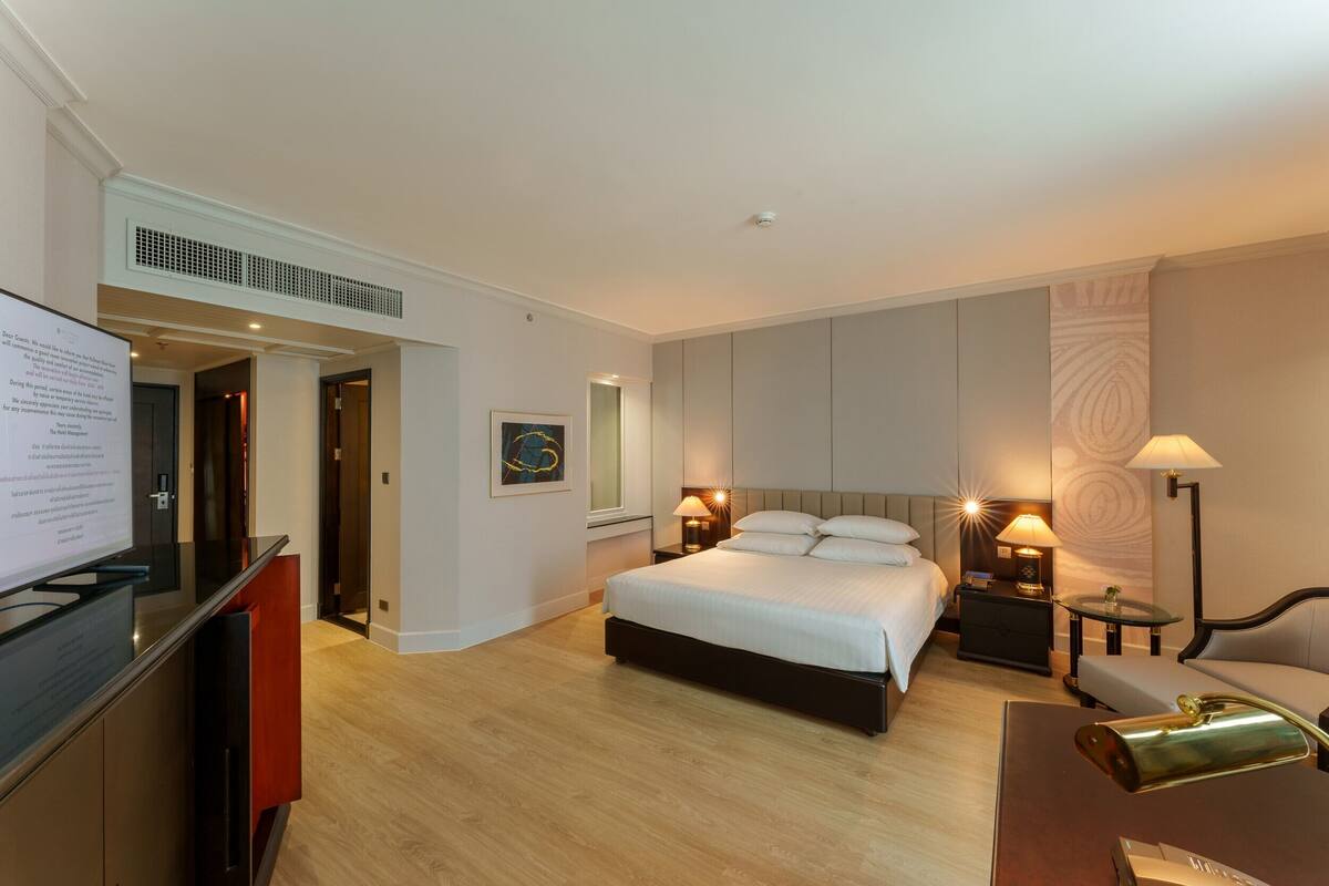 Ein Hotelzimmer mit Bett, Nachttischen, Schreibtisch, Stuhl und Fernseher.