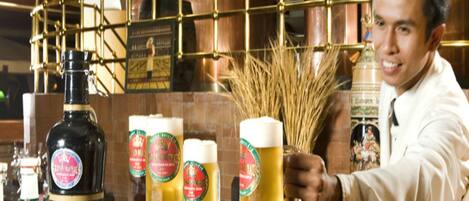 Un camarero sosteniendo una jarra de cerveza, con una barra de grifos al fondo.