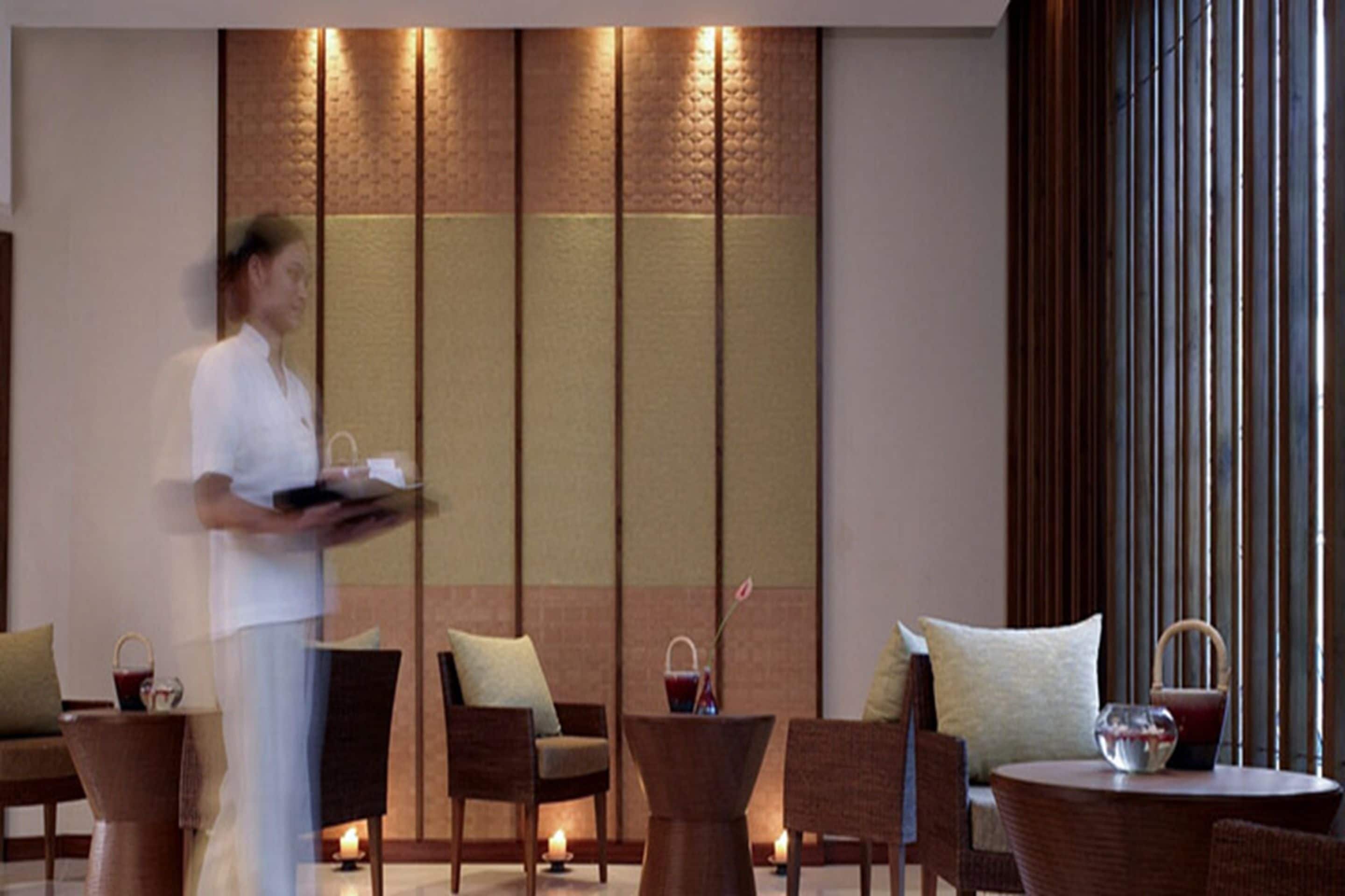 A hotel lobby with a reception area, seating arrangements, and a decorative wall.