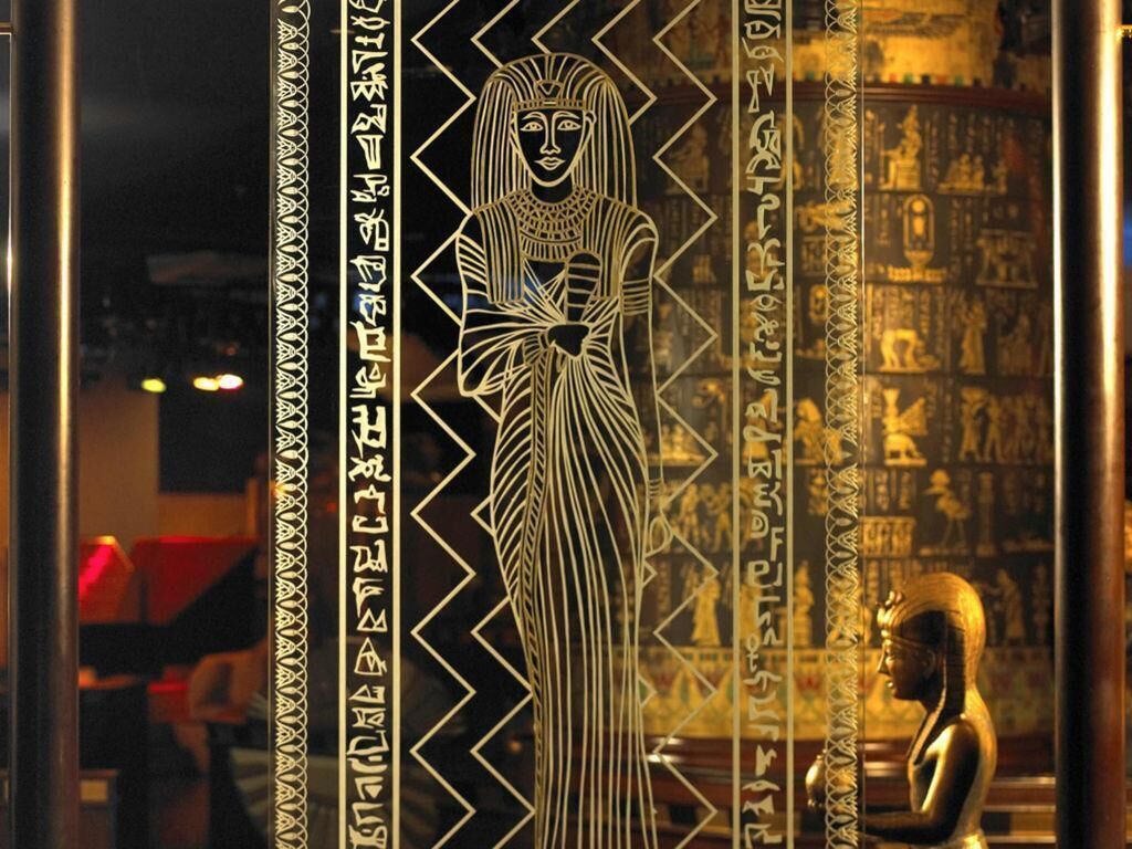 A room with a large Egyptian-themed wall mural, a golden statue, and hieroglyphic inscriptions.