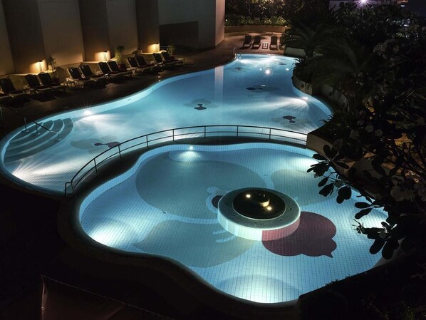 Ein Pool mit einem runden Becken, umgeben von Liegestühlen und einem Geländer.