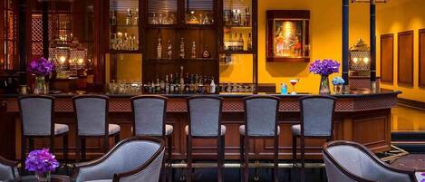 Zona de bar con diversas opciones de asientos y una barra bien surtida.