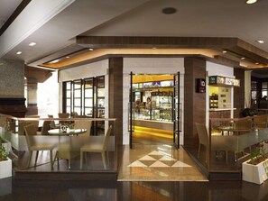 A modern interior with a glass partition separating a dining area from a bakery. - The Heritage Grand Khon Kaen Hotel (Khon Kaen)
