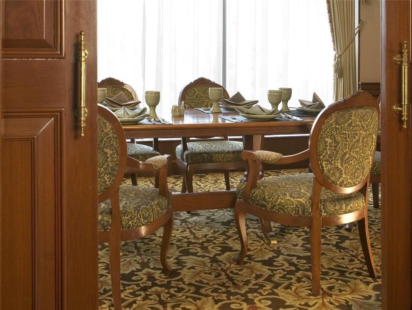 A dining area with a wooden table set for four, surrounded by upholstered chairs with patterned upholstery.
