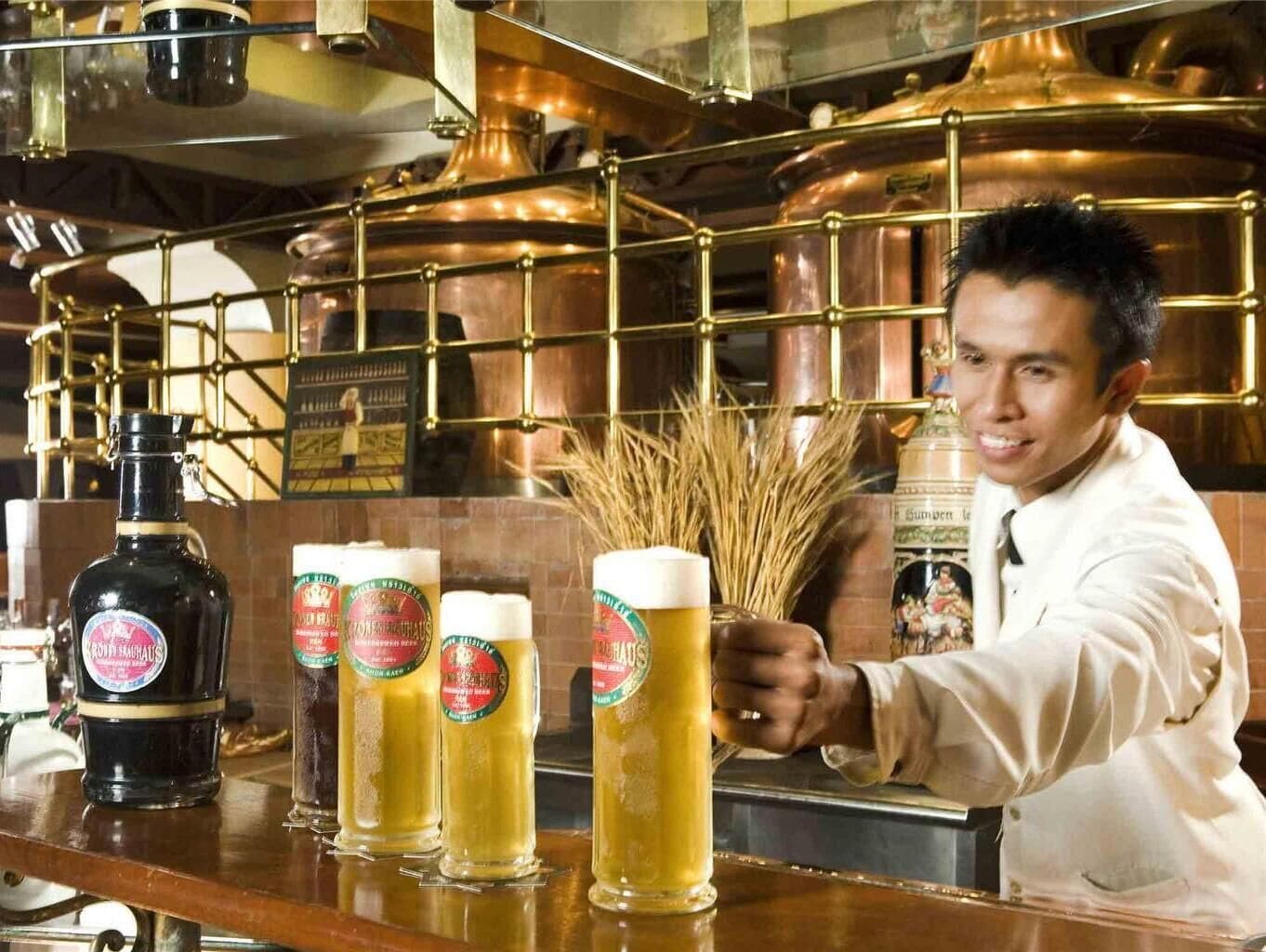 A bar with copper brewing equipment and bottles of beer.