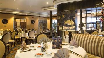 A dining area with round tables, chairs, and traditional Chinese table settings.