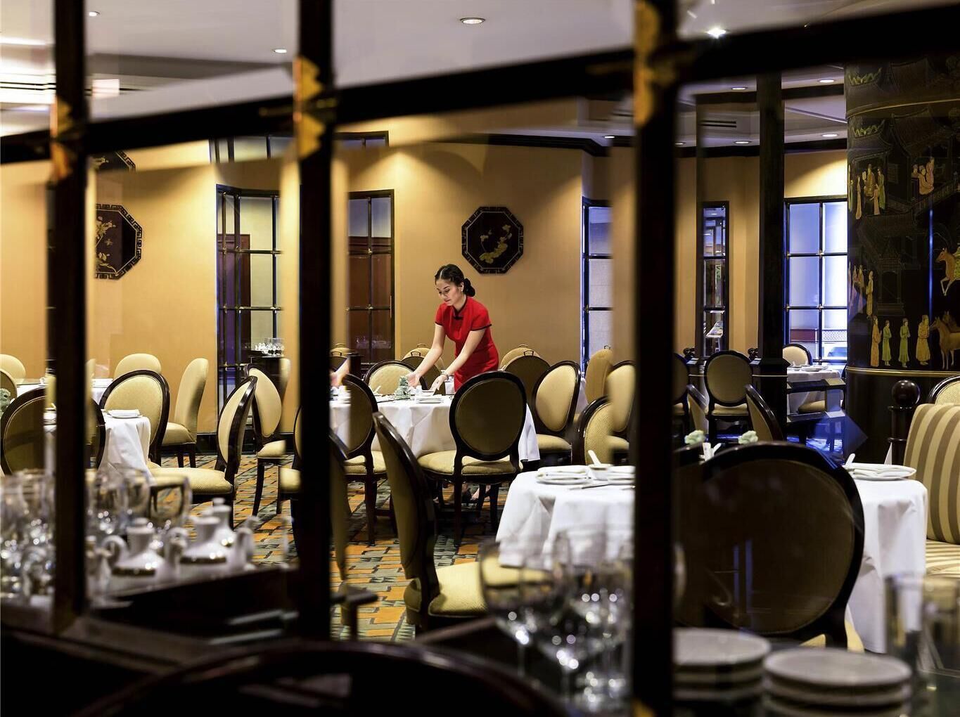 Un restaurante con mesas dispuestas para comer, un camarero atendiendo una mesa, y decoración tradicional.