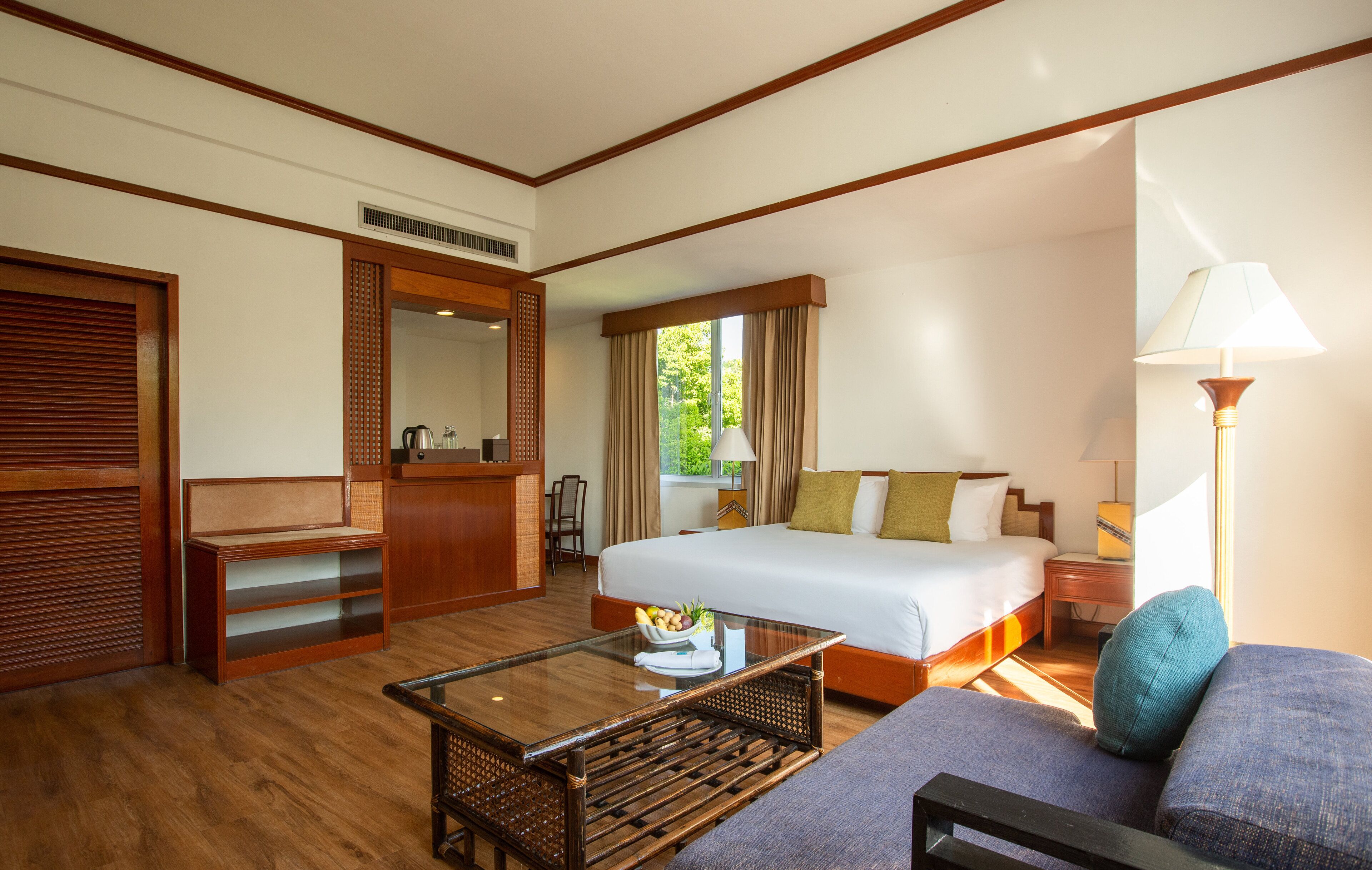 A hotel room with a large bed, a sitting area with a sofa and a coffee table, a desk, and a wardrobe.