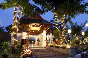 A wooden gazebo with string lights, surrounded by potted plants and a pathway leading to the entrance. - Mae Sot Hotel (Mae Sot)