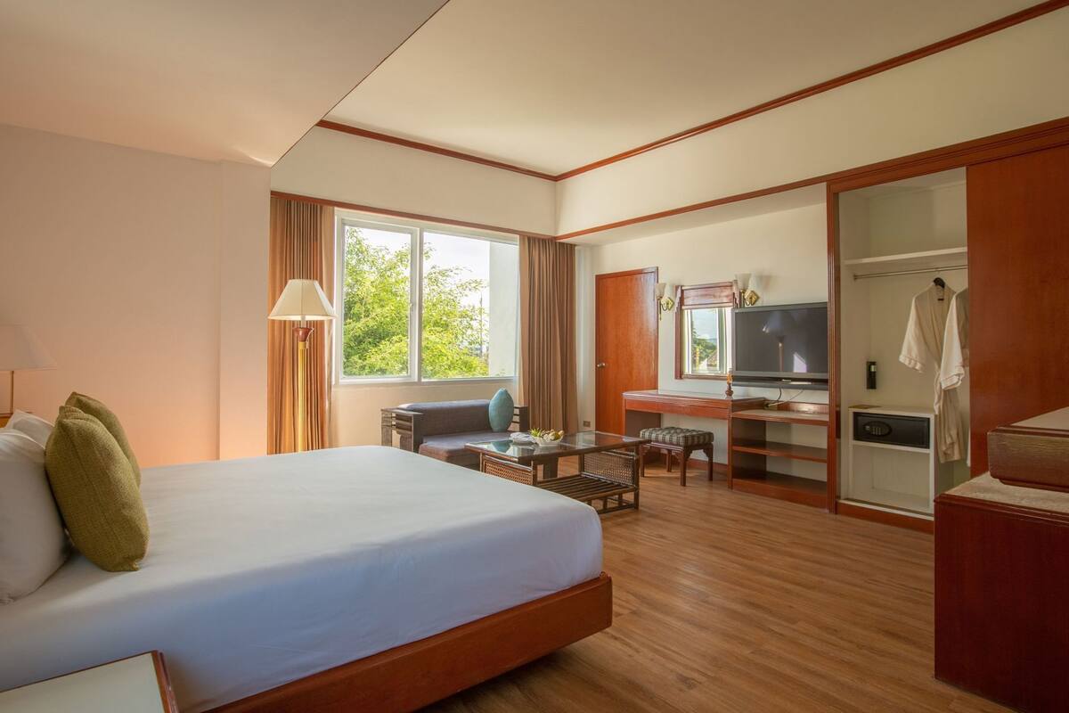 Une chambre d’hôtel équipée d’un lit, d’un bureau, d’une télévision et d’une armoire.