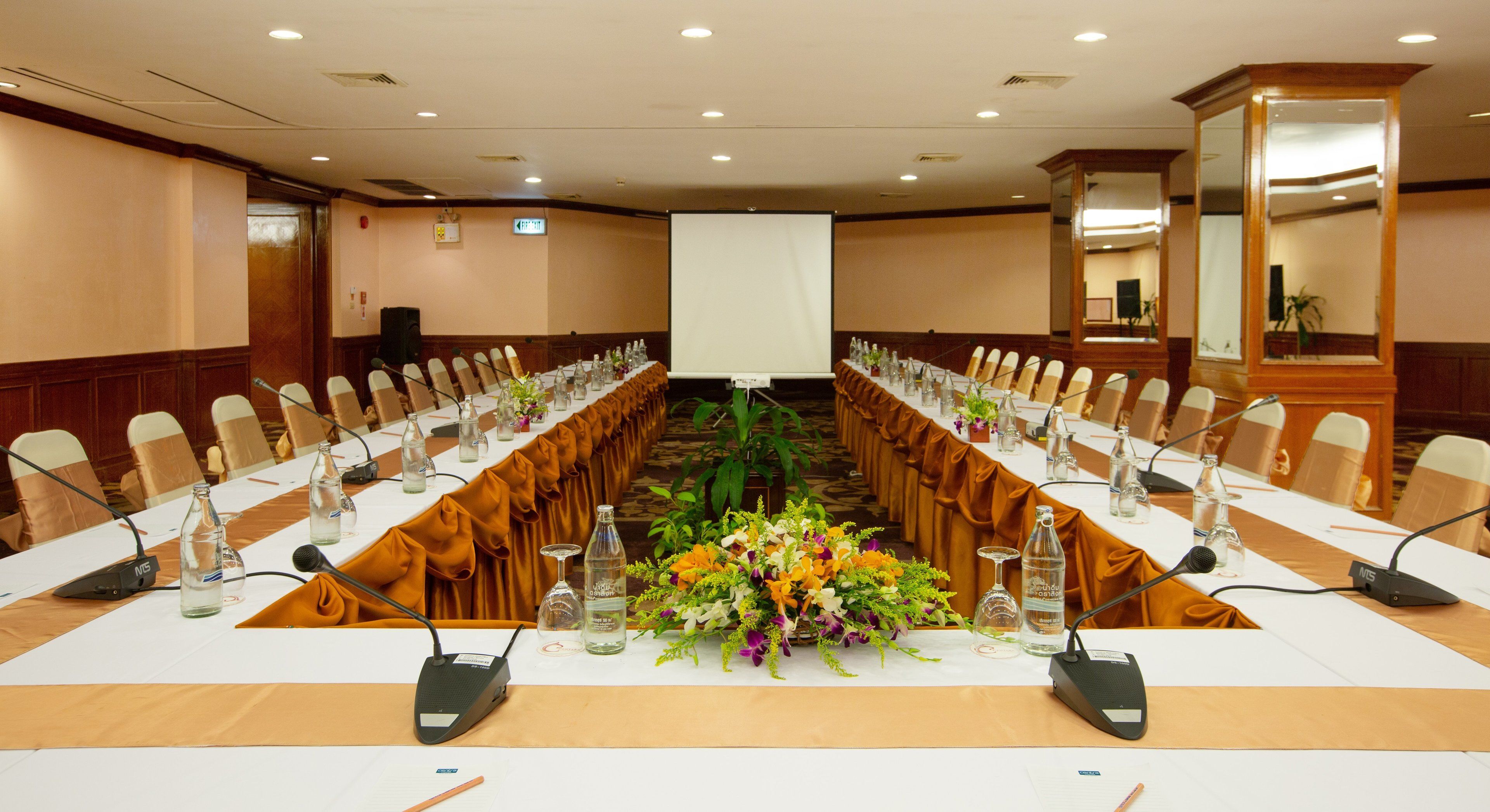 Una sala conferenze con un lungo tavolo, microfoni e sedie.
