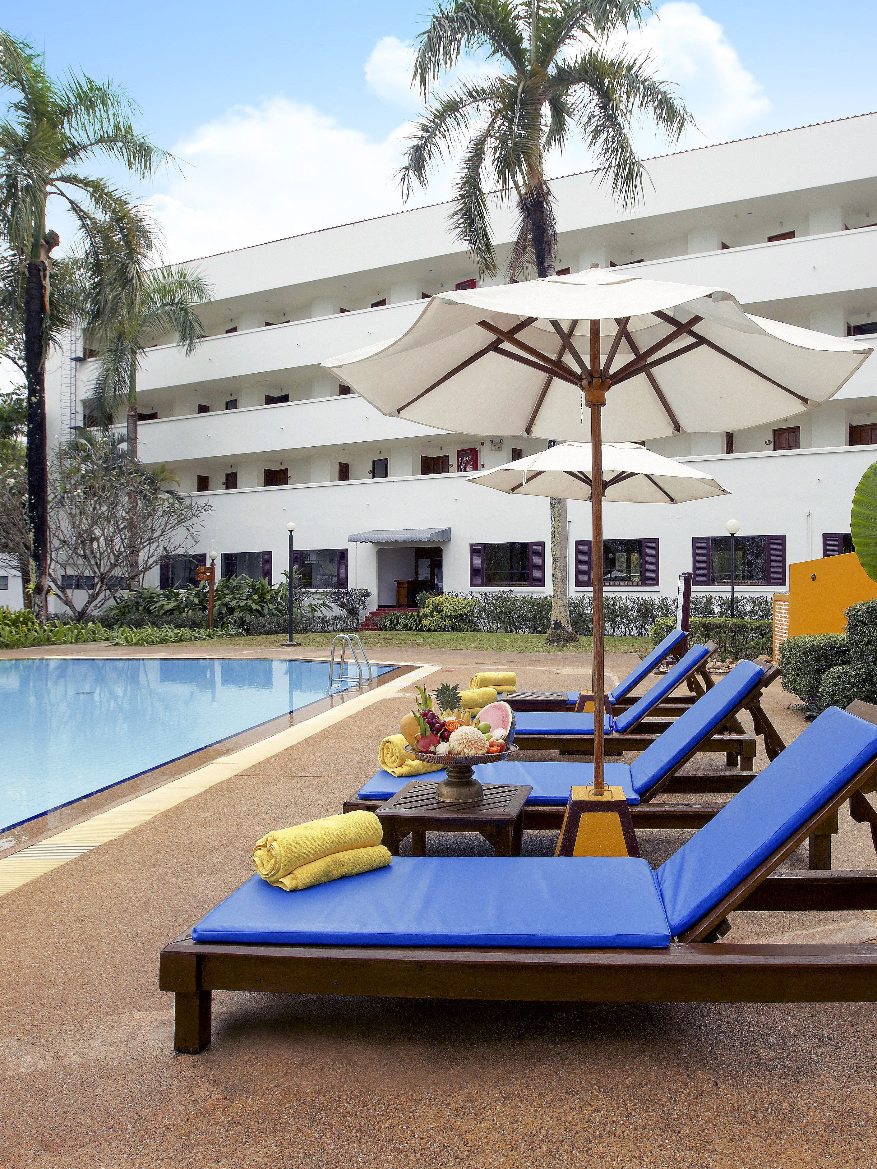 A poolside area with lounge chairs, umbrellas, and a fruit bowl.