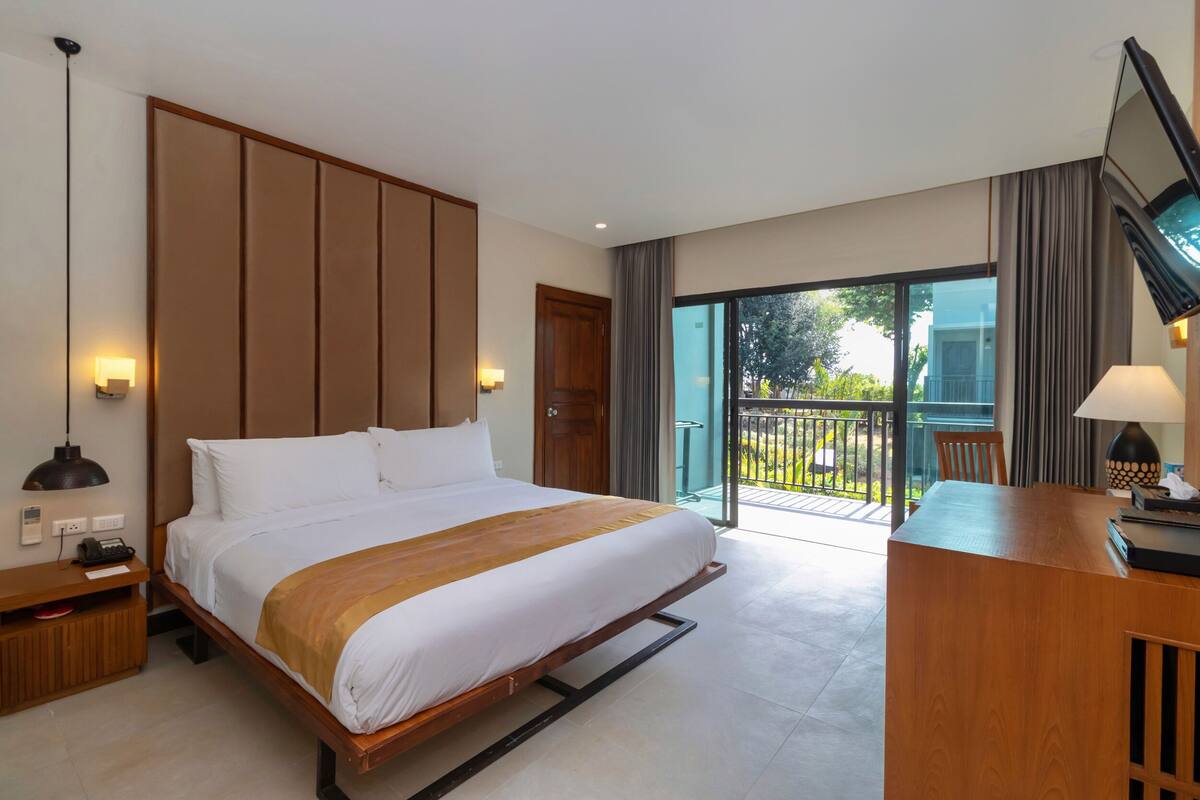 Une chambre d’hôtel avec un lit, une table de chevet, une lampe et une vue sur l’extérieur.