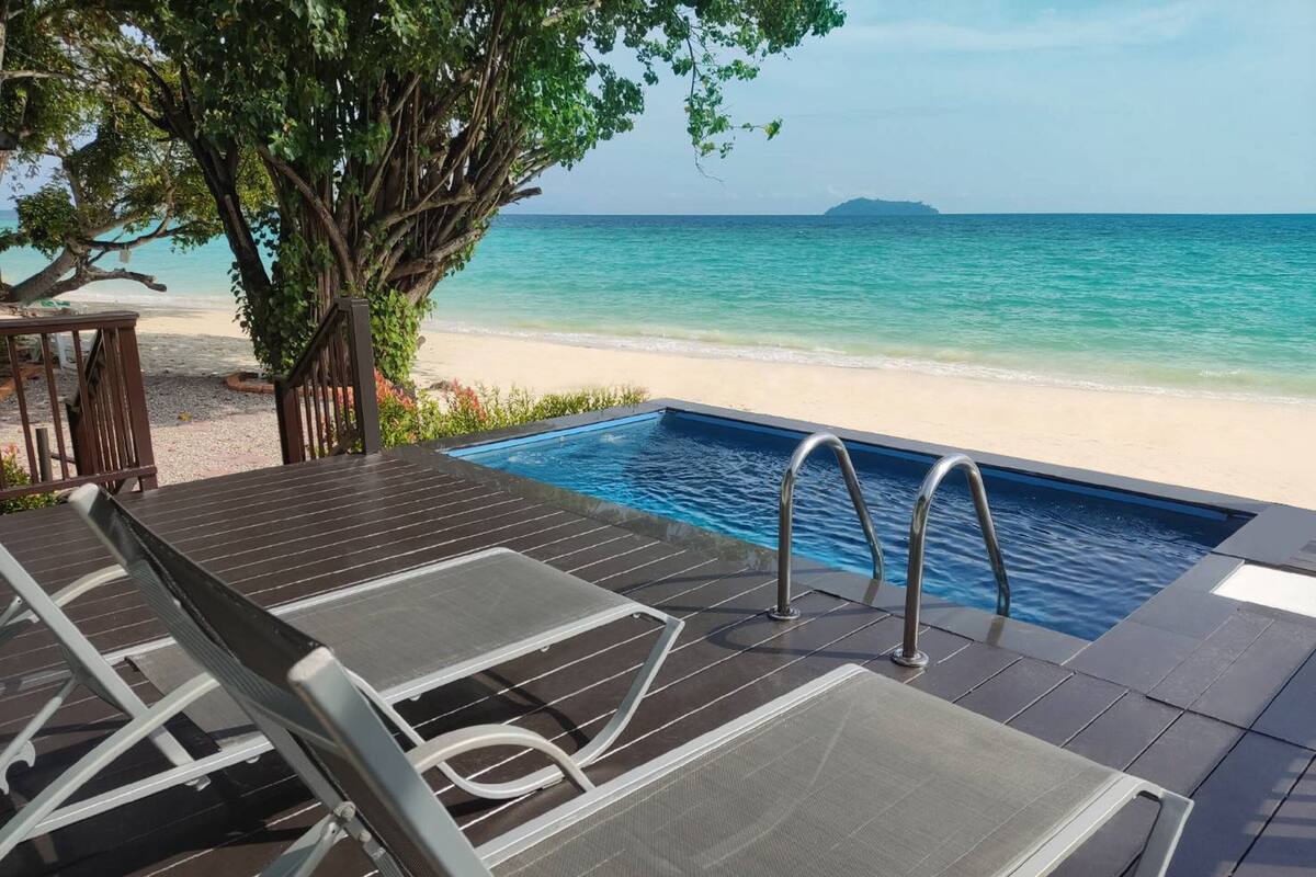 Un espace aménagé au bord de la piscine, offrant une vue sur la plage et l’océan.
