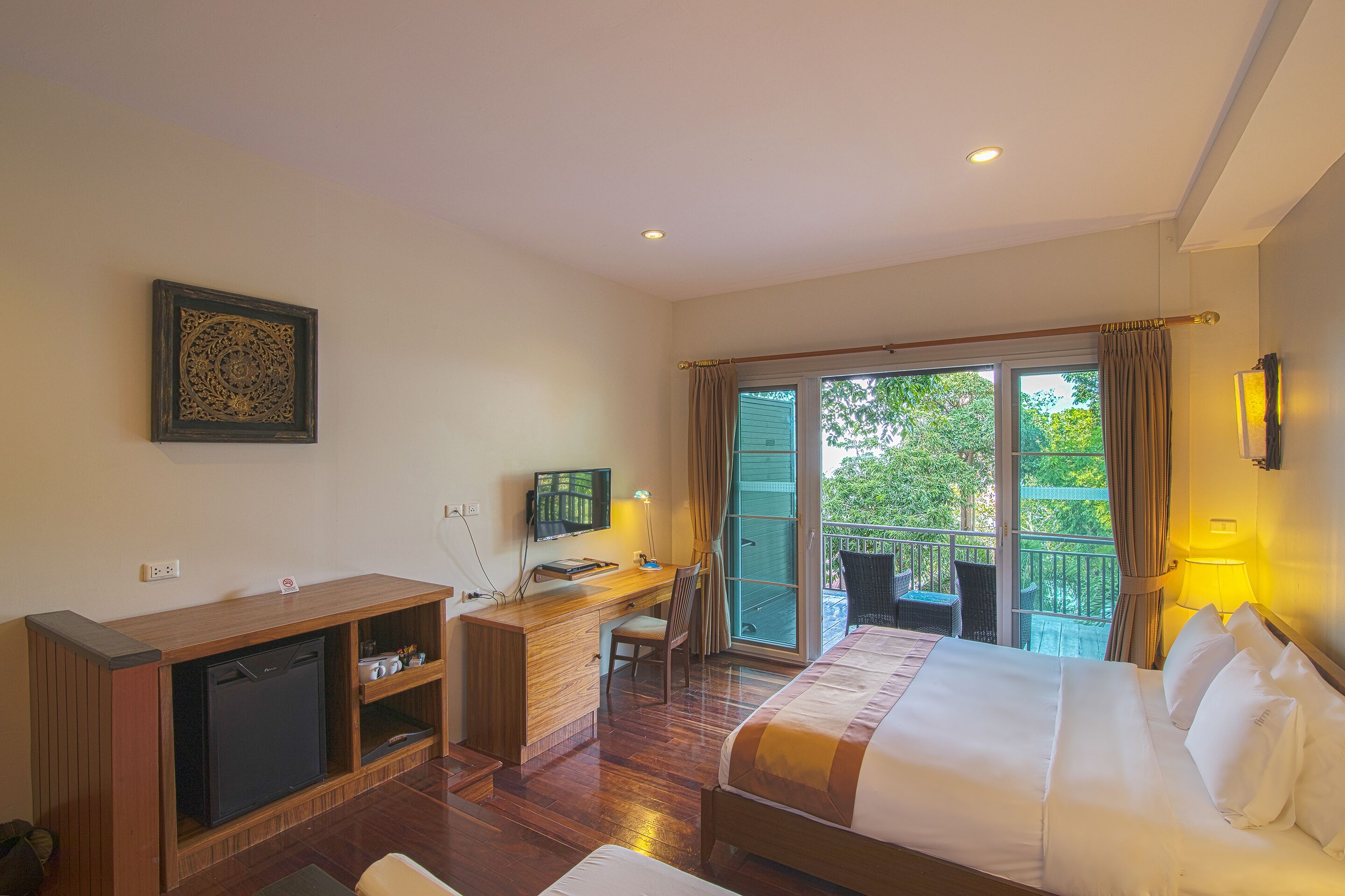 A hotel room with a bed, desk, and a television.
