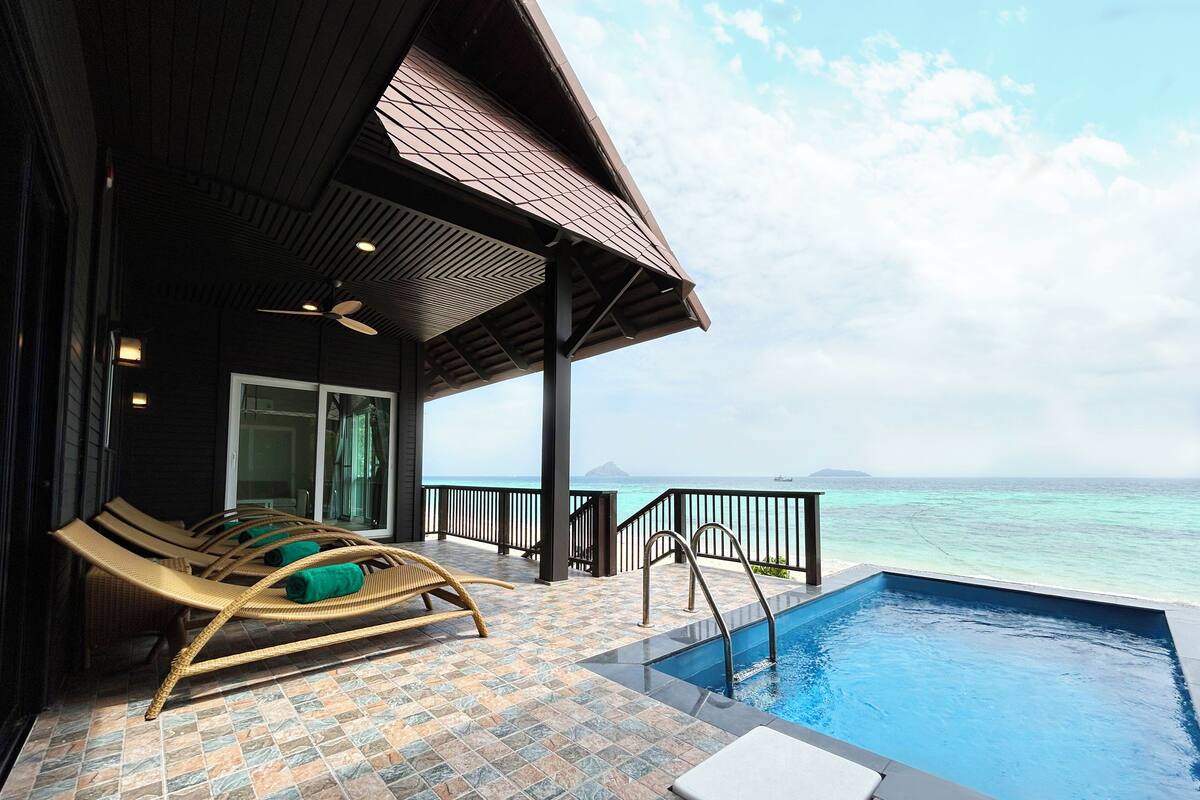 Un espace aménagé au bord de la piscine, avec des chaises longues, une piscine et une vue sur l’océan.