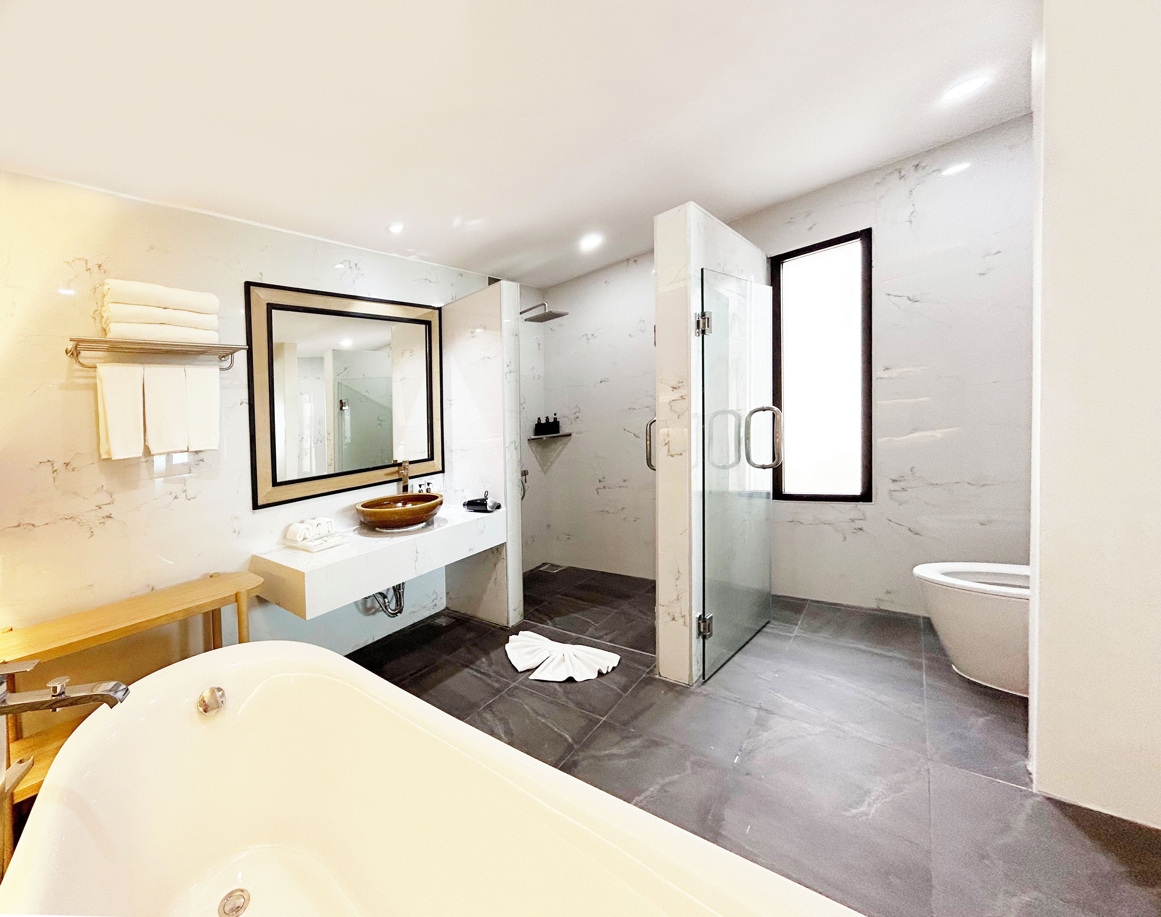 A modern bathroom with a bathtub, a vanity with a mirror, a glass-enclosed shower, and a toilet.