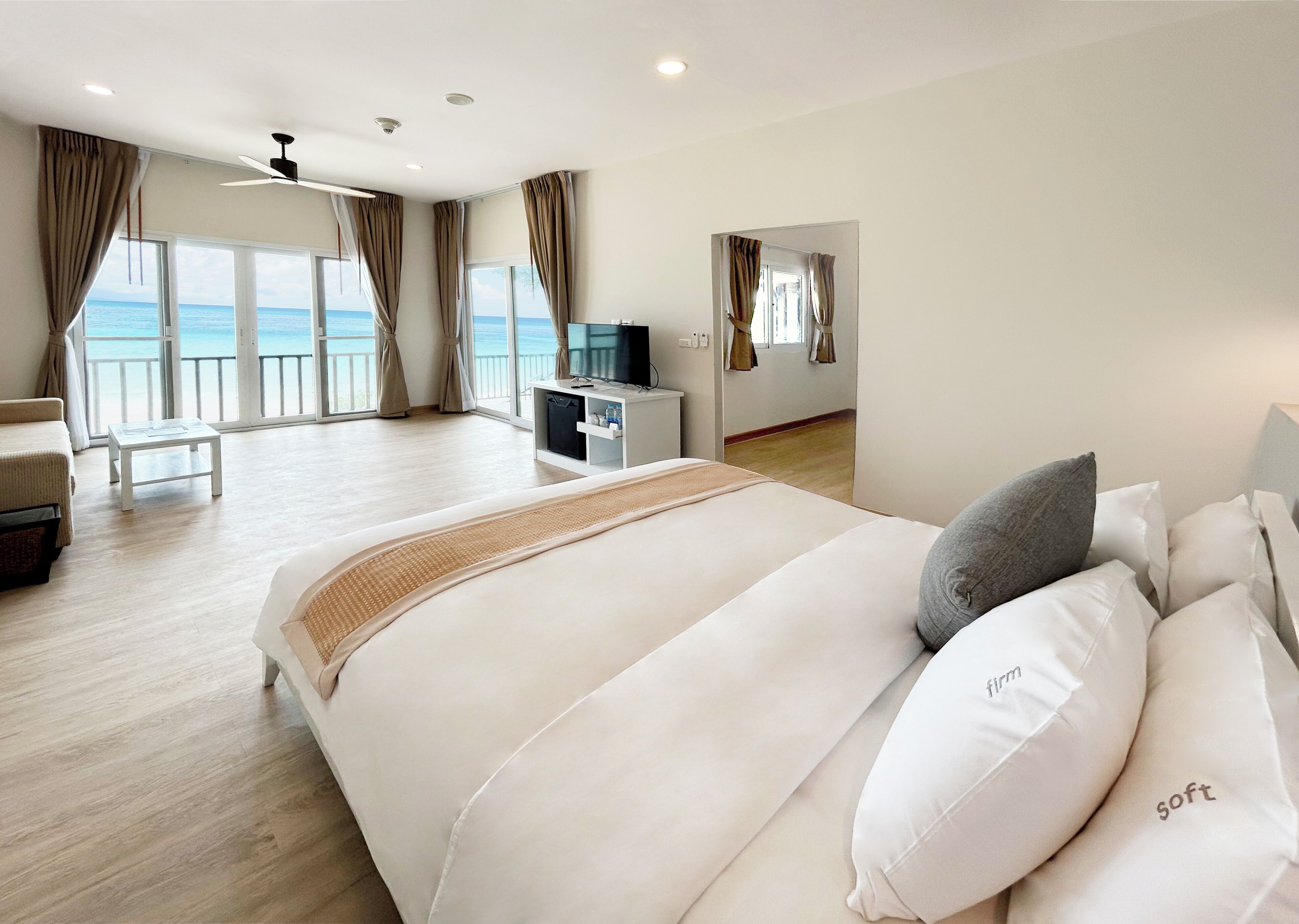 Une chambre d’hôtel spacieuse, dotée d’un grand lit, d’un bureau avec une télévision et d’un balcon offrant une vue sur la mer.